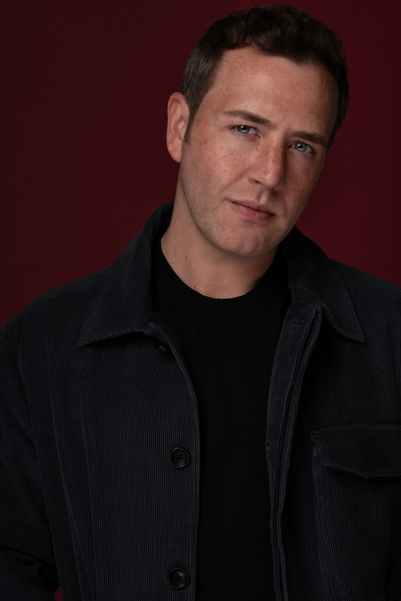 Kevin Pettei — black jacket, red backdrop